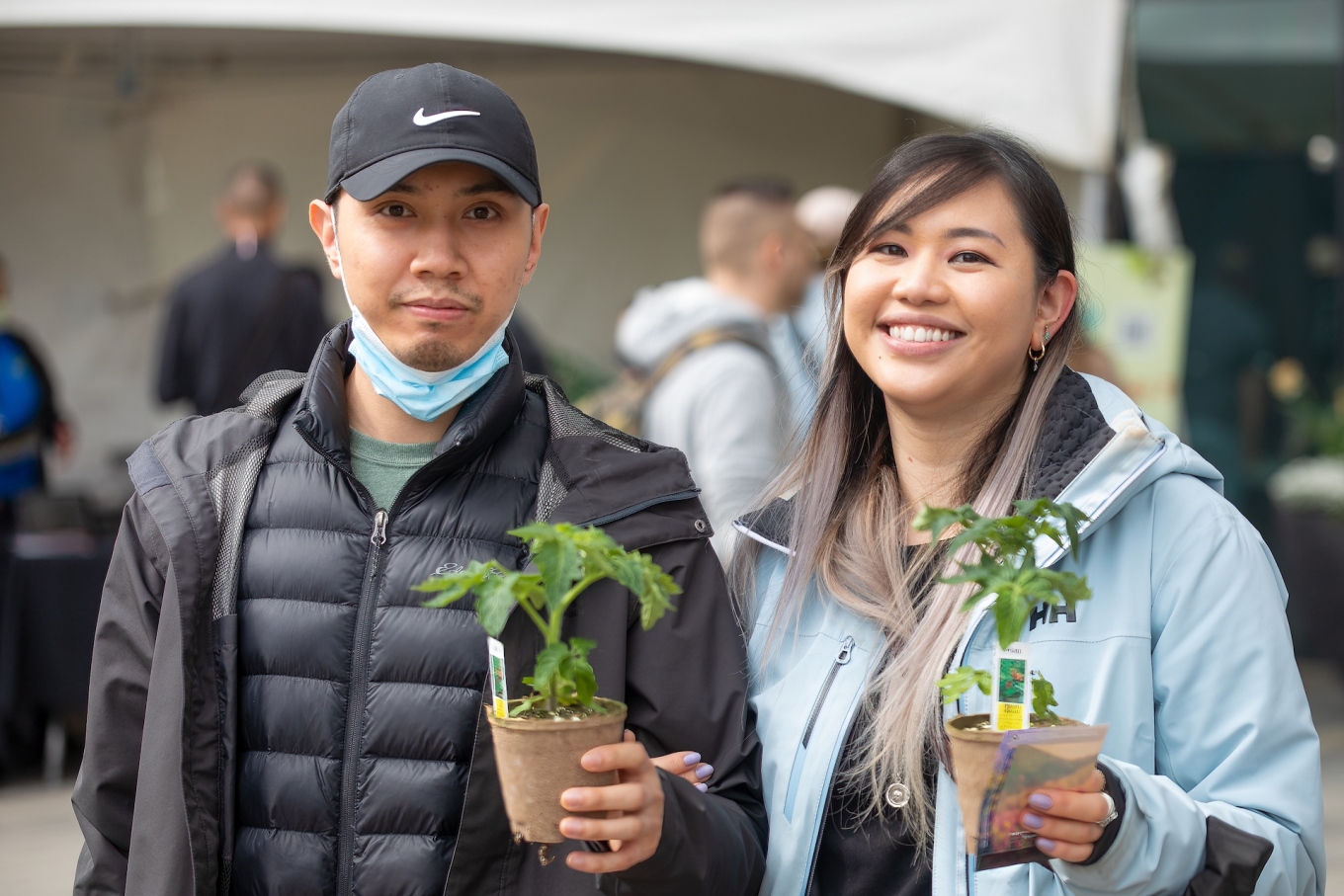 Young adult couple pose holding their newly bought potted plants